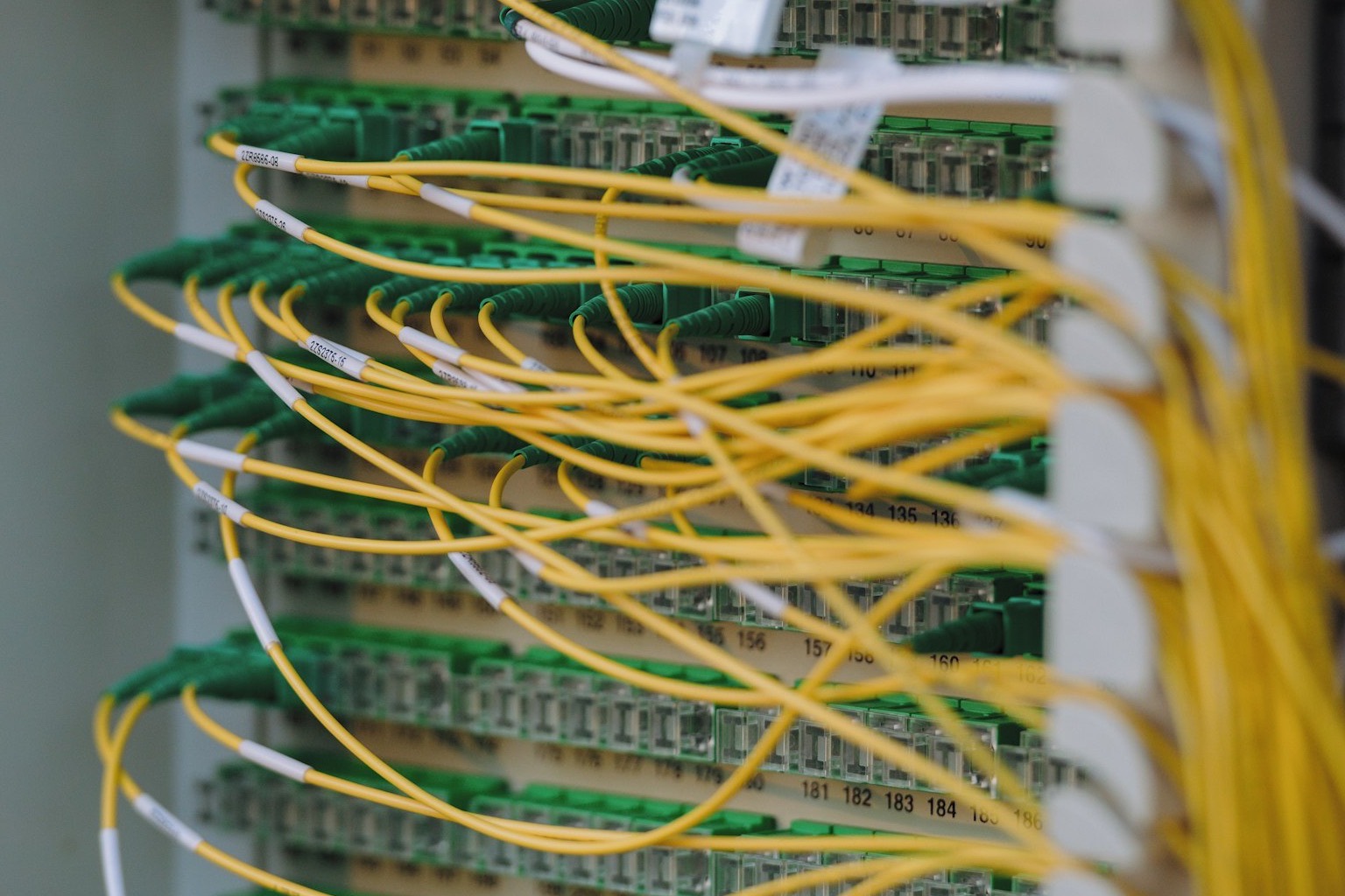 Yellow fibre-optic cabling patched into a data centre panel, the physical infrastructure AI access runs over